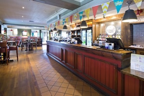 Eine Bar mit einer Theke, Hockern und einer Speisekarte.