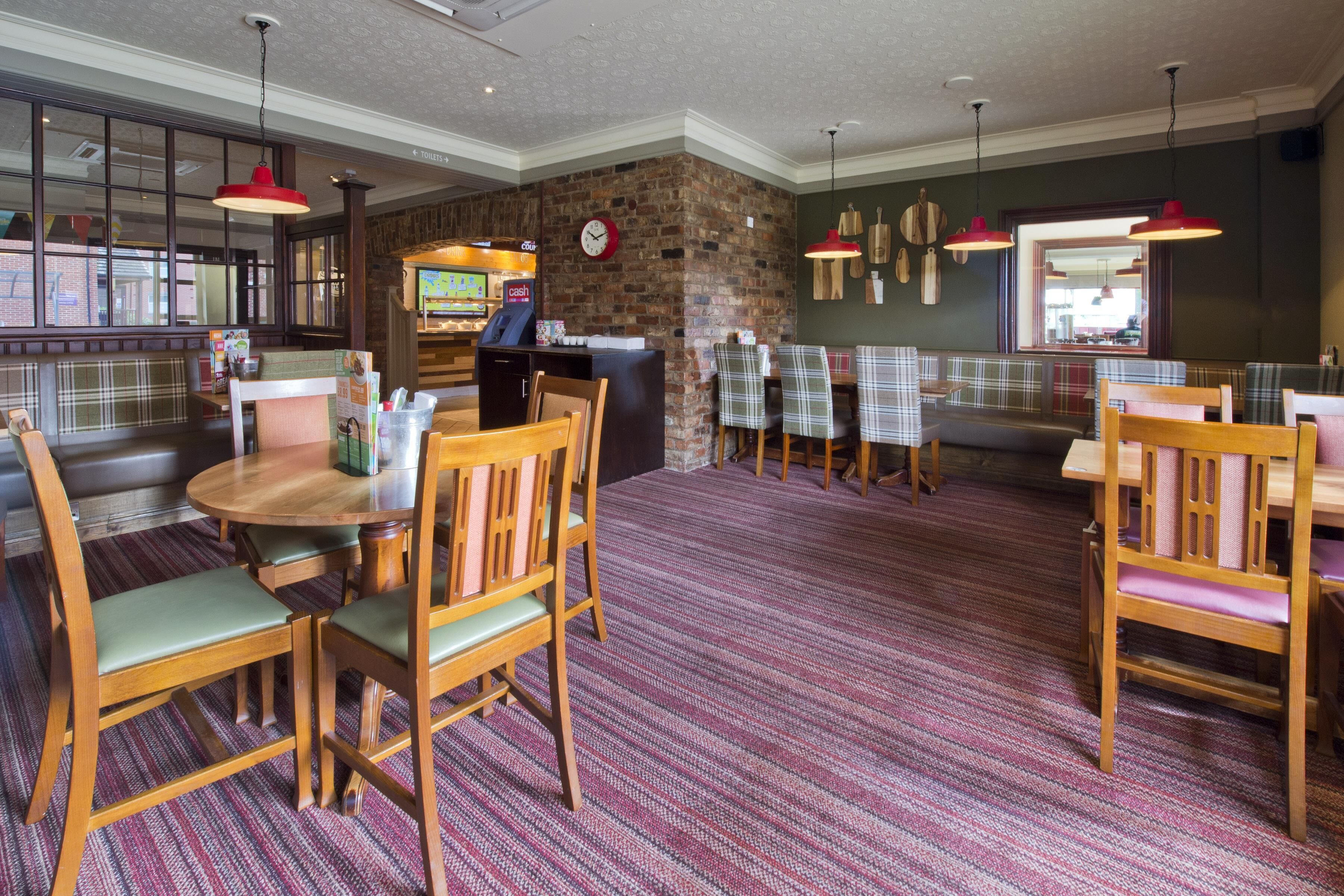 Un restaurante con pared de ladrillo, muebles de madera y un reloj.