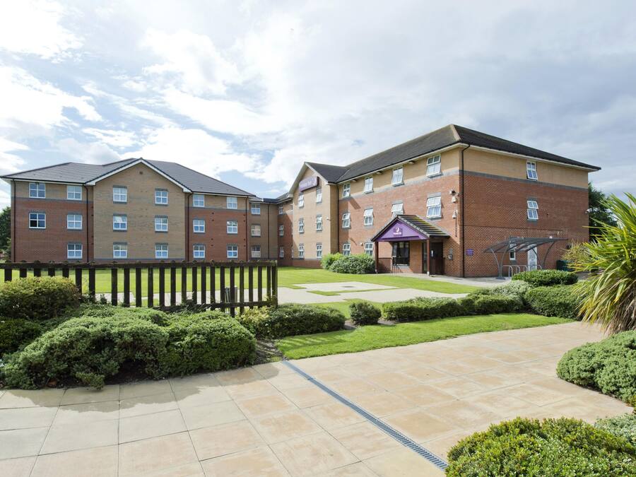 A multi-story building with a brick facade, a gated entrance, and a well-maintained lawn.