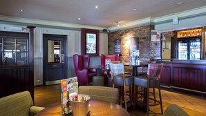 A bar area with stools, a wooden table, and a menu stand. - Premier Inn Doncaster Central East (Doncaster)