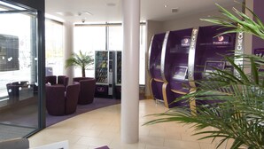 A hotel lobby with check-in counters, seating areas, and a vending machine. - Premier Inn Doncaster Central (Doncaster)