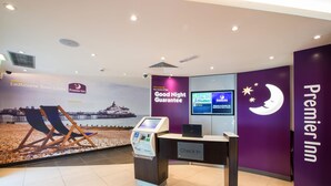 A Premier Inn reception area with a check-in desk, a digital kiosk, and a wall mural. - Premier Inn Eastbourne Town Centre (Eastbourne)