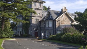A large stone building with a tower, arched windows, and a red door. - Premier Inn Edinburgh A1 - Musselburgh (Musselburgh)