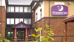 A Premier Inn hotel entrance with a brick facade, a purple sign, and a gated driveway. - Premier Inn Livingston - M8 Jct3 (Livingston)