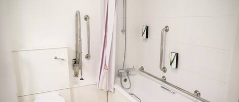 A bathroom with a white toilet, a shower with a handheld showerhead, and grab bars.