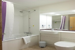 Bathroom features a bathtub, shower, sink, and toilet, with a mirror above the sink and a towel rack.
