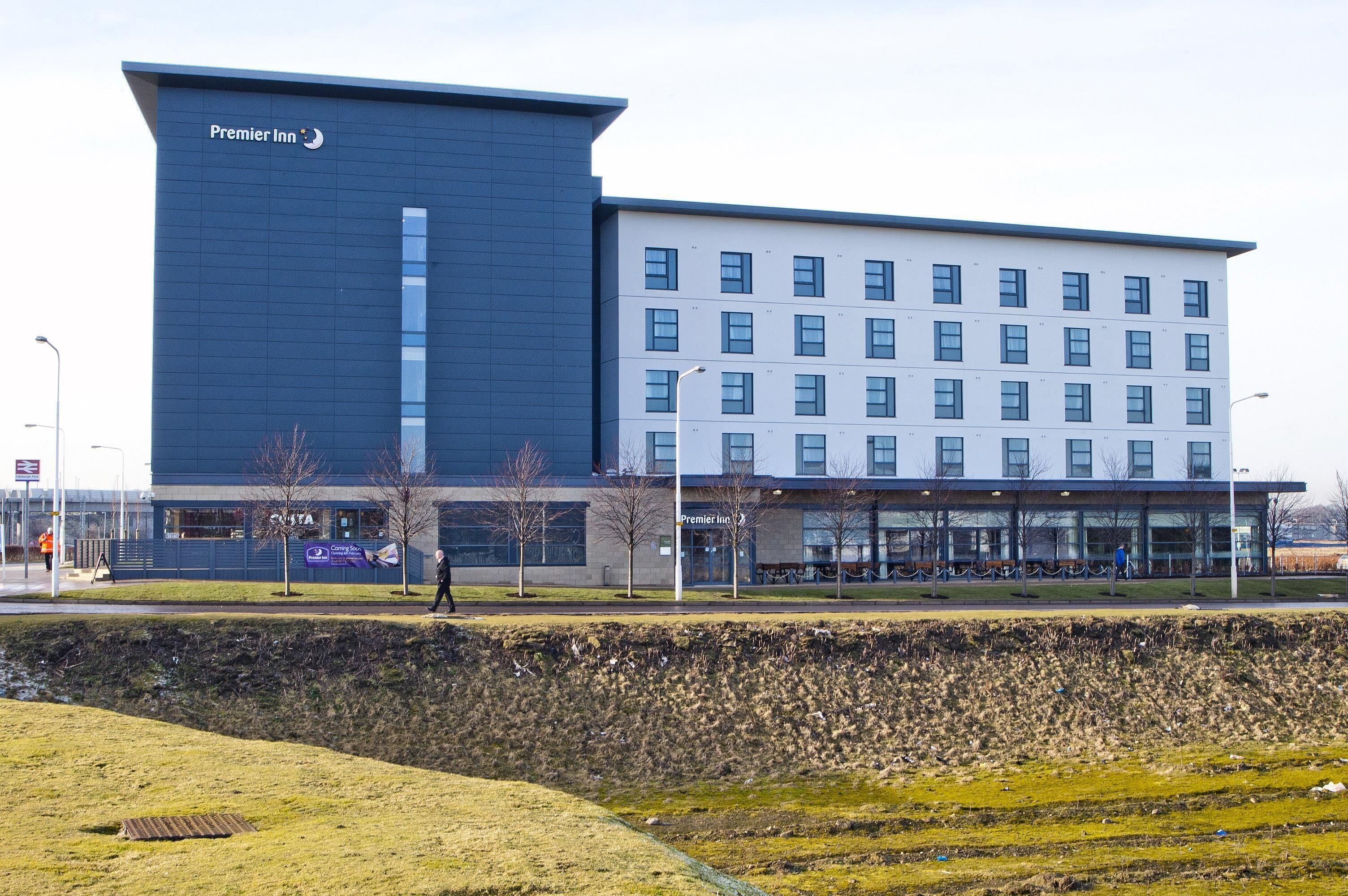 En moderne hotelbygning med et tydeligt 'Premier Inn' skilt, en flad facade og flere vinduer.