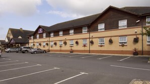 A hotel with a brick facade, multiple windows, and a parking lot.