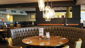 Un restaurant amb taula rodona, seients de boxa de pell i il·luminació penjant.