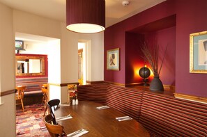 Ein Essbereich mit einem langen Tisch, Bänken und Blick auf ein Restaurant.