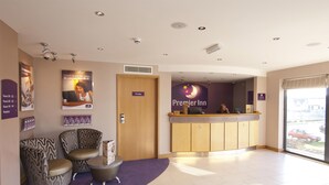 Un'area reception di un hotel con un banco accettazione, una porta per una stanza privata e una scrivania della reception.