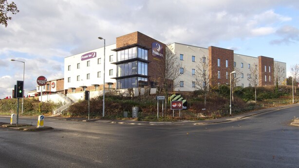 A multi-story hotel with a prominent Premier Inn sign, a staircase leading to the entrance, and a clear road in front. - Premier Inn Exeter - M5 J29 (Exeter)