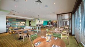 A restaurant with round tables, chairs, and a menu stand. - Premier Inn Exmouth Seafront (Exmouth)