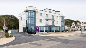 A modern hotel with a curved facade, large windows, and a car park sign. - Premier Inn Exmouth Seafront (Exmouth)