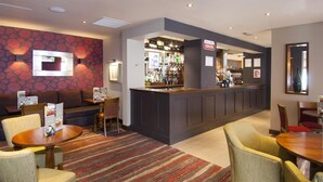 A hotel lobby with a bar area, seating arrangements, and a patterned wall. - Premier Inn Camberley (Camberley)