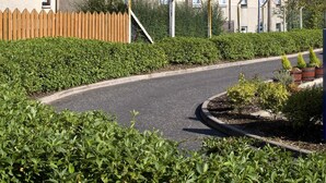 A multi-story hotel with a brown roof, a wooden fence, and a well-maintained garden area. - Premier Inn Glasgow - Cumbernauld (Cumbernauld)