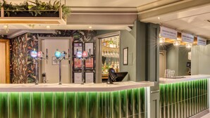 A bar area with a green-lit counter, multiple beer taps, and a menu board. - Premier Inn Glasgow Airport (Paisley)