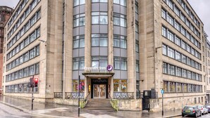 A multi-story building with a central entrance, large windows, and a visible fire escape. - Premier Inn Glasgow City - George Square (Glasgow)