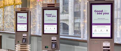 A hotel check-in kiosk with a 'Good to see you' message, a QR code, and a digital screen for finding reservations.