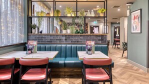 A restaurant interior with booths, tables, and potted plants. - Premier Inn Glasgow City - George Square (Glasgow)