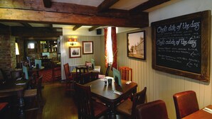 A restaurant interior with wooden beams, tables, chairs, and a chalkboard menu. - Premier Inn Gloucester - Barnwood (Gloucester)