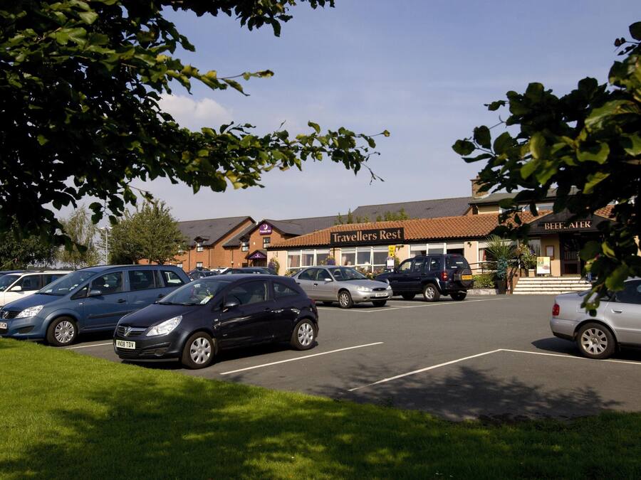 Un parking où sont garées plusieurs voitures, un bâtiment portant l’inscription « Travelers Rest », et un restaurant appelé « Beef & Ale ».