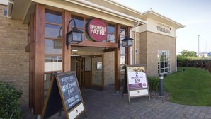 Un edificio con un cartello che recita 'Brewers Fayre' e 'Whittle Inn'. Due cartelli sono posti di fronte: uno pubblicizza 'Martyn's Bait' e l'altro offre '2 pasti a £9'.
