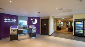 A hotel lobby with a check-in kiosk, a vending machine, and a sign reading 'Good Night Guarantee'. - Premier Inn Harrogate Town Centre (Harrogate)