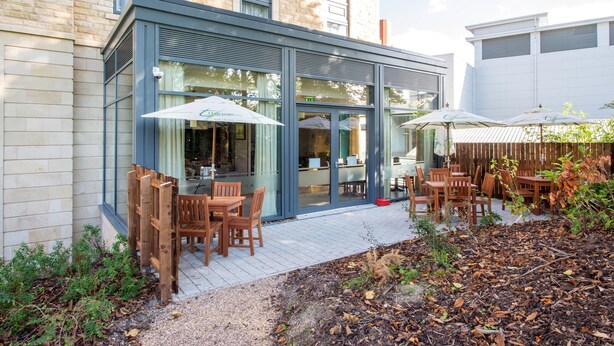 A building with a brick facade, large windows, and outdoor seating with umbrellas. - Premier Inn Harrogate Town Centre (Harrogate)