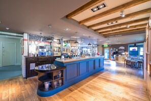 A bar area with a long counter, shelves with glasses, and a sign indicating the direction to toilets. - Premier Inn Haverfordwest - North/A40 (Haverfordwest)