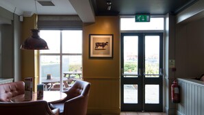 A restaurant interior with a dining area, a framed picture on the wall, and a view through the door. - Premier Inn Hull North (Hull)