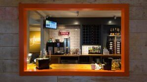 A bar area with a coffee machine, a sign that says 'Proud to Serve Costa,' and a wine rack. - Premier Inn Hull North (Hull)