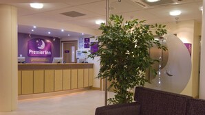 Un espace d’accueil d’hôtel comprenant un comptoir de réception, une plante et un coin salon.