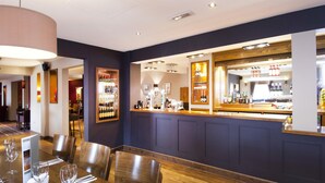 A restaurant with a bar area, wooden tables, and chairs. - Premier Inn High Wycombe Central (High Wycombe)