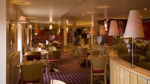 A restaurant with tables, chairs, and hanging lamps. - Premier Inn Inverness Millburn Rd (Inverness)