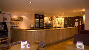 A restaurant with a wooden counter, bar area, and seating with menus. - Premier Inn Inverness Millburn Rd (Inverness)