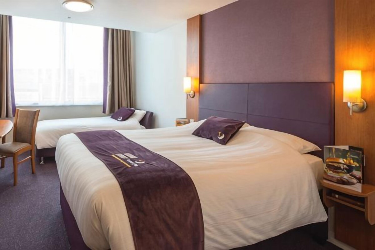 A hotel room with two beds, a desk, and a chair.