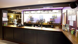 A bar area with a counter, shelves of bottles, and various bar equipment. - Premier Inn Inverness Centre - River Ness (Inverness)