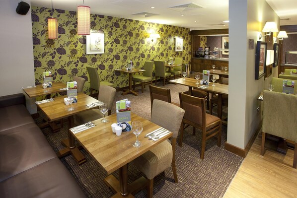 A restaurant with multiple tables, chairs, and a patterned wallpaper. - Premier Inn Inverness Centre - River Ness (Inverness)