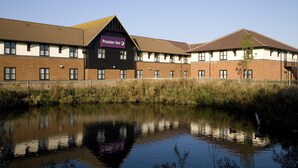Un hôtel dont la façade est ornée d’une enseigne indiquant « Premier Inn », avec une façade en briques et un plan d’eau devant.