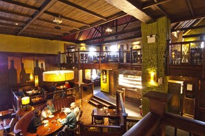 Ein Restaurant mit Holzinneneinrichtung, mehreren Essbereichen und einer Bar.