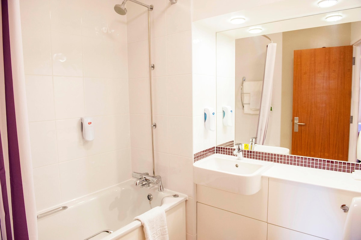 A modern bathroom with a bathtub, shower, and two sinks.