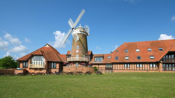 A building with a windmill, picnic tables, and a grassy field. - Premier Inn Milton Keynes South (Milton Keynes)