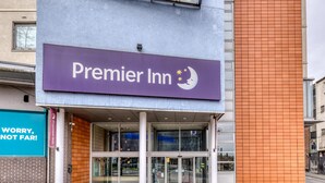 De ingang van een Premier Inn hotel met een paars bord, glazen deuren en een bakstenen gevel.