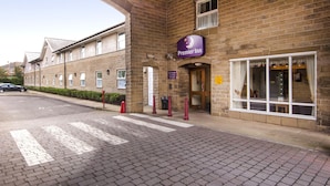 Un bâtiment en briques avec une enseigne « Premier Inn », une entrée fermée par un portail et un passage piéton clairement indiqué.
