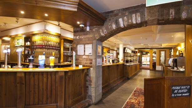 A bar area with multiple taps and a sign indicating a wait time. - Premier Inn Leeds South - Birstall (Bradford)