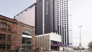 Ein Hotel mit einem gut sichtbaren 'Premier Inn'-Schild, einem 'Capita'-Schild und einem modernen Gebäude mit reflektierenden Fenstern.