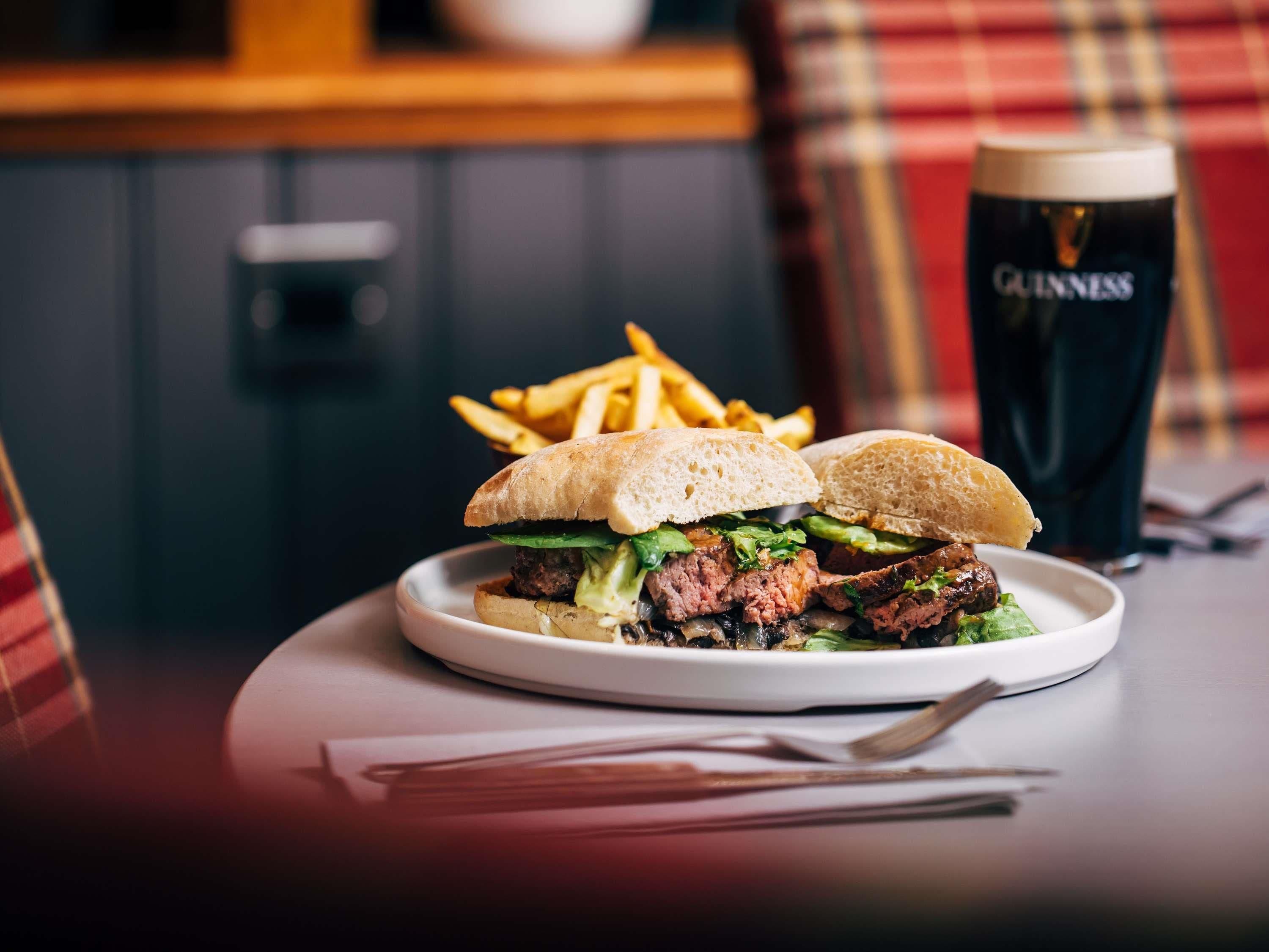 A meal consisting of a sandwich and fries on a plate, accompanied by a glass of beer.
