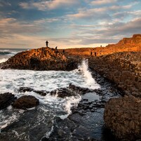 Una zona costera rocosa con olas rompiendo contra un muro de piedra.