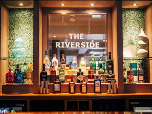 A bar with a variety of liquor bottles and a sign that reads 'THE RIVERSIDE'.